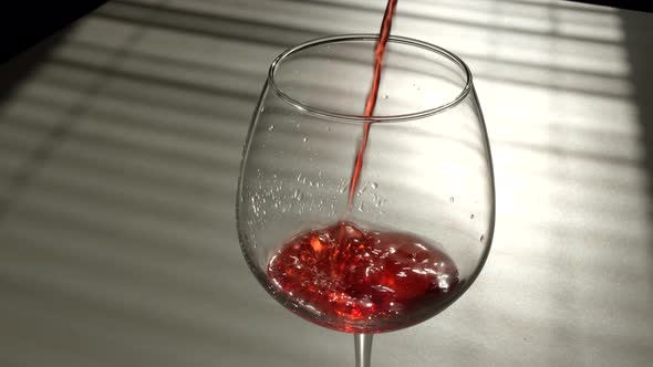 Red Wine is Poured Into a Glass on a White Background