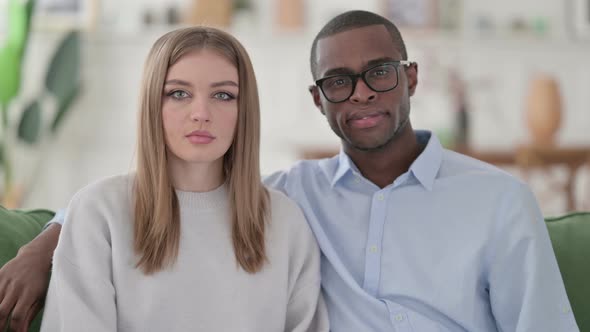 Serious Mixed Race Couple Looking at the Camera Home