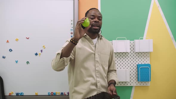 An African American Teacher Teaches a Group of Children 1012 Years Old Studying Animals and Fruits