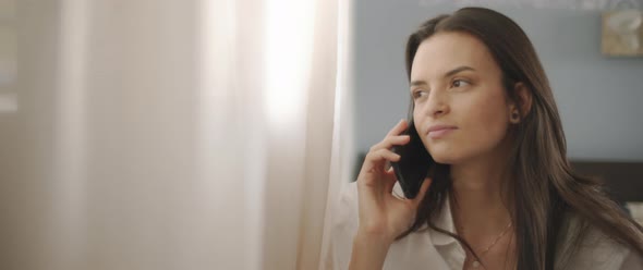 Close up of a woman in white shirt talking to someone on the phone and smiling