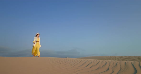 Stylish Woman Walking in Fashionable Clothes By the Rippled Sand Desert Surface