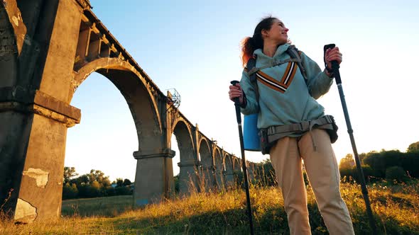 A Woman with Sports Inventory Is Standing Near a Massive Bridge