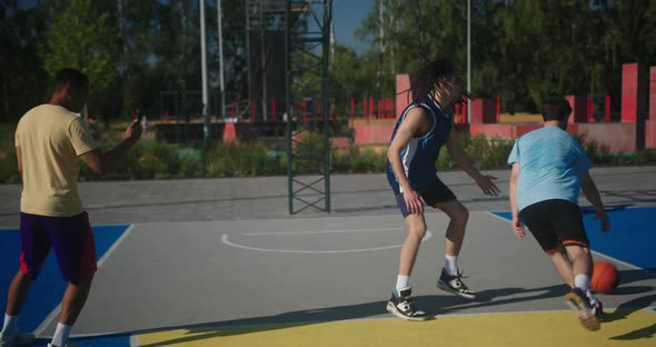 Hispanic Man Records Players Playing Basketball on Court