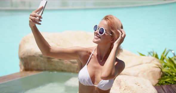 Smiling Woman in Swimwear Taking Selfie on Smartphone Showing Two Fingers