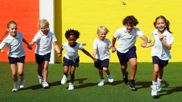 School kids holding hands and running in campus