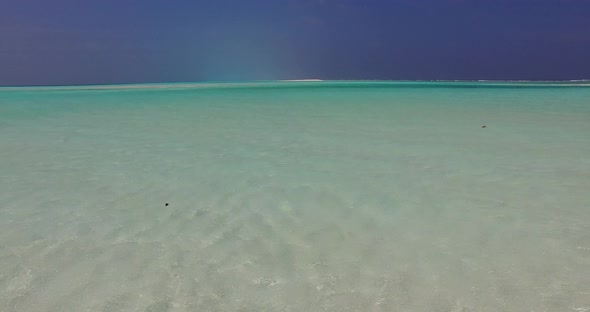 Wide flying island view of a white paradise beach and blue water background in best quality 4K