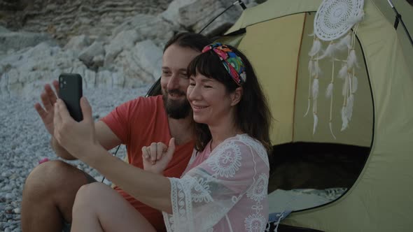 Travel Couple having a video chat talking smiling  using cellphone near the sea