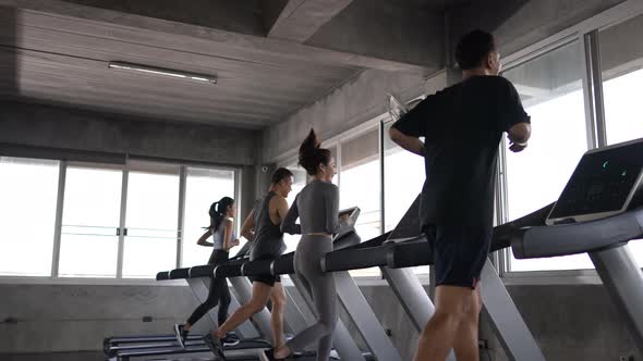 4K Group of Asian man and woman jogging on treadmill together at fitness gym.