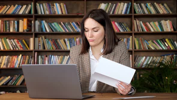 Businesswoman Types on Grey Laptop Looking at Bank Letter