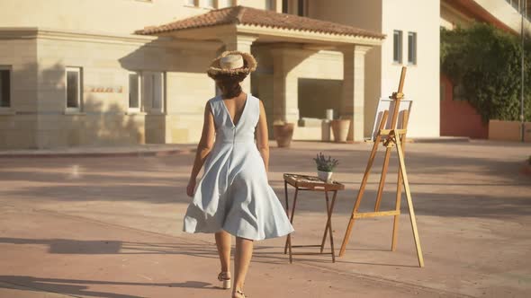 Wide Shot Back View of Gorgeous Slim Confident Woman Walking to Easel in Sunlight in Slow Motion