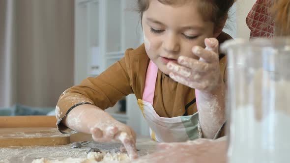 Mom and Daughter Prepare Holiday Cookies Together in the Kitchen. A Little Girl Helps Her Mother