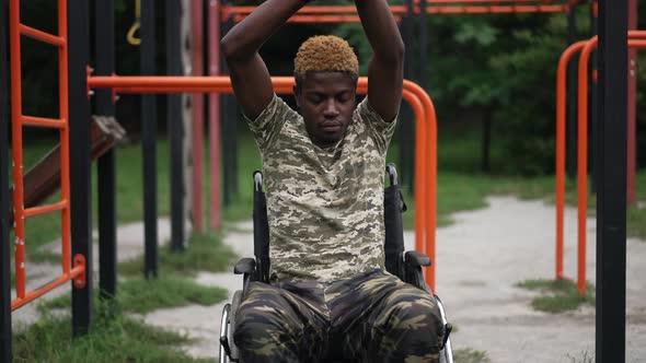 Confident Fit African American Man in Wheelchair Warming Up Outdoors with Sports Equipment at