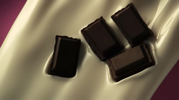 Chocolate pieces blend with pouring milk in slow motion