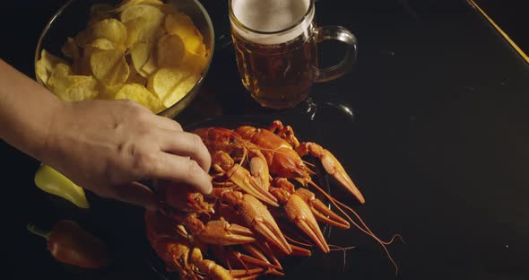 Close Up View of Man Arm Taking Lobsters with Foamy Bear Pouring in Glass and Crisp Chips on