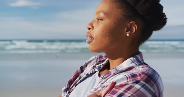 African american woman looking away at the beach on sunny day