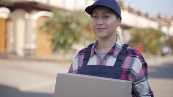 Smiling Female Courier Walking with Cardboard Box