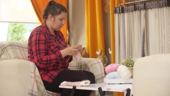 An Adult Woman Knits Little Pink Socks From a Thin Yarn