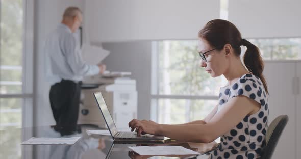 Side View of Caucasian Businesswoman Sitting at Desk in Office Using Computer