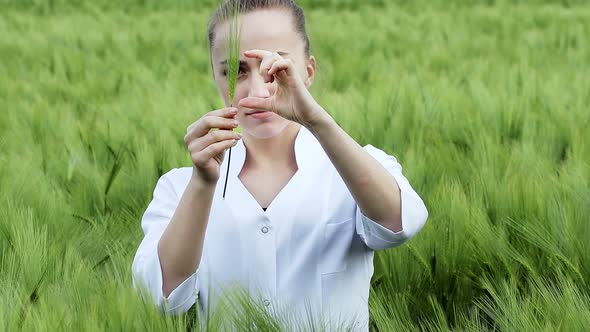 Ecologist in a white coat and glasses examining plants.