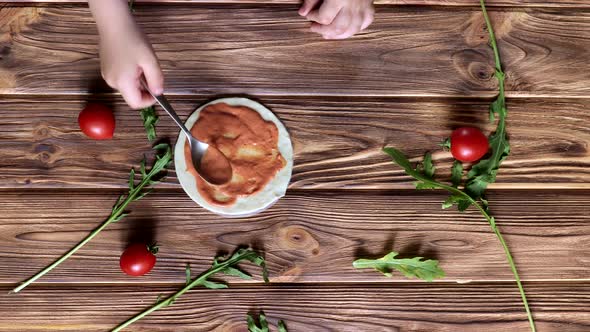 Little child is cooking italian pizza with tomatoes, olives and ham. Process food preparation