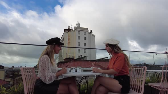 Female friends drinking coffee into cups in outdoor cafe