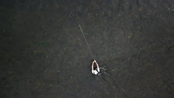 Bird's Eye Drone Shot above a man Fly Fishing in the Provo River in the Mountains of Utah. The man i