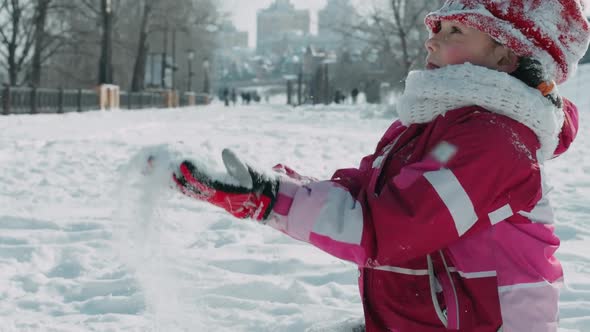 Teenager Girl Throwing Snow in Winter Park. Girl Playing with Snow at Winter