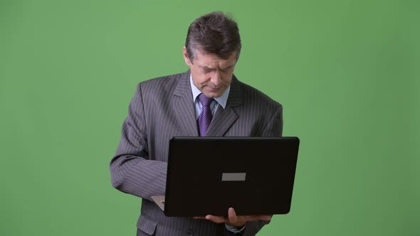 Mature Handsome Businessman Against Green Background