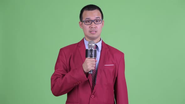 Nervous Asian Businessman with Eyeglasses Using Microphone