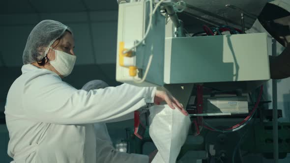 A Female Worker Packs Sugar Using Machine on Conveyor Belt of Sugar Beet Plant