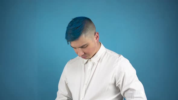 A Young Man in Glasses with Blue Hair Is Dressing Up a Suit. An Alternative Person Fastens Buttons