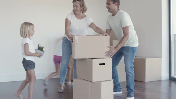 Positive Parents and Two Daughters Packing Things for Moving