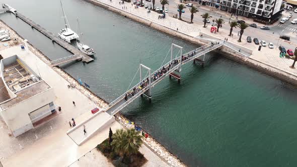 Crowd of people crossing a pedestrian bridge at Marina de Lagos, Algarve