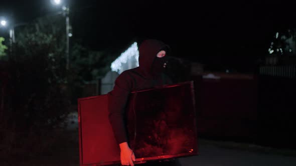 A Thief in a Mask Carries a Stolen TV Late at Night is Caught By the Police with Flashing Lights