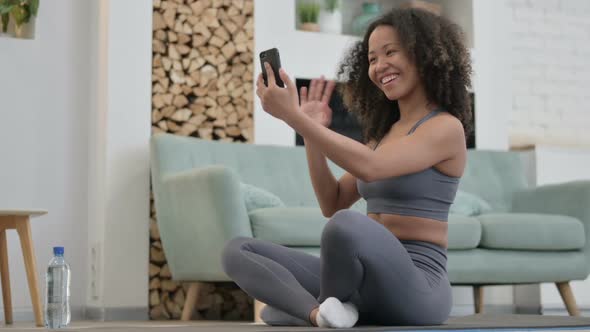 Video Chat on Smartphone By African Woman Sitting on Fitness Mat