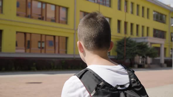 A Caucasian Teenage Boy Looks Around  Rear Closeup  a School in the Background