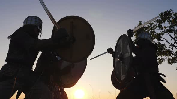 Silhouettes of Vikings Warriors Fighting with Swords, Shields. Contre-jour