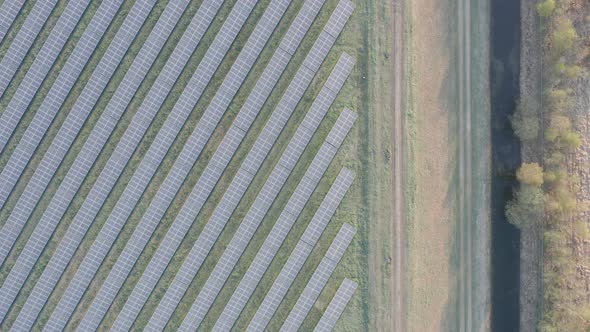 Aerial Top Down view solar panels on field next to river powering factory. Field of solar panels tha