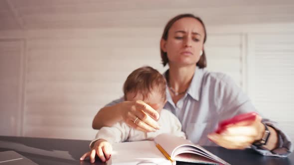 A Young Mother is Working at Home Using Computer While She's Taking Care of Her Baby