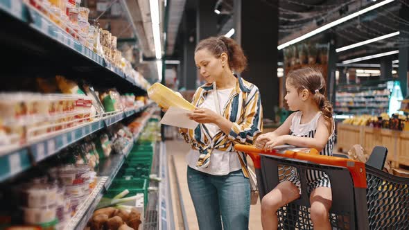 Woman Takes Packed Products From the Shelf Packed Mushrooms and Puts Them in a Trolley