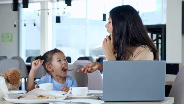 Mother Feeds Daughter in Restaurant