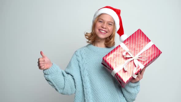 Happy Young Girl in Santa Claus Cap Holding Present