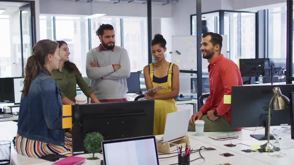 Diverse group of work colleagues looking at computer monitor and talking