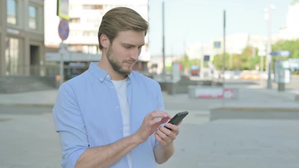Man Browsing Internet on Smartphone Outdoor