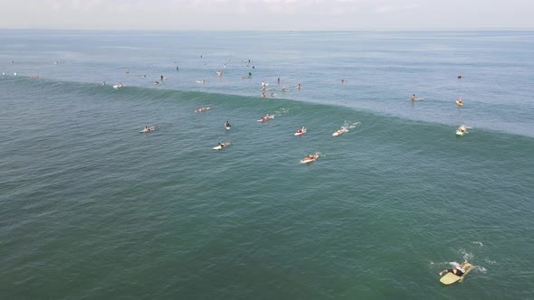 Aerial view of people surfing on waves with surfboards when vacation in Bali, Indonesia .