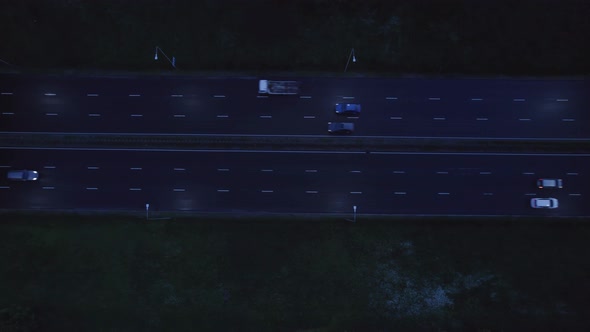 Aerial drone view of a multi-level highway crossroad with moving cars at sunset. Cars are moving alo