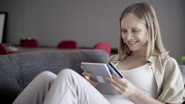 Smiling Pregnant Woman Shopping Online with Tablet