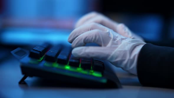 Closeup Side View of Hands in White Gloves Typing on Backlit Keyboard