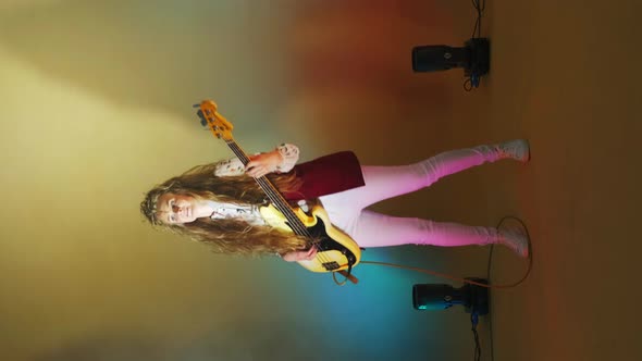 Vertical Video of a Woman Playing a Guitar but Changing Background Light and Strobe Lights of a