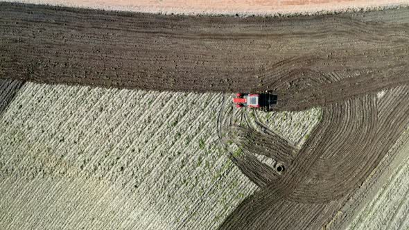 Red tractor working on spring spring field, Poland, aerial view